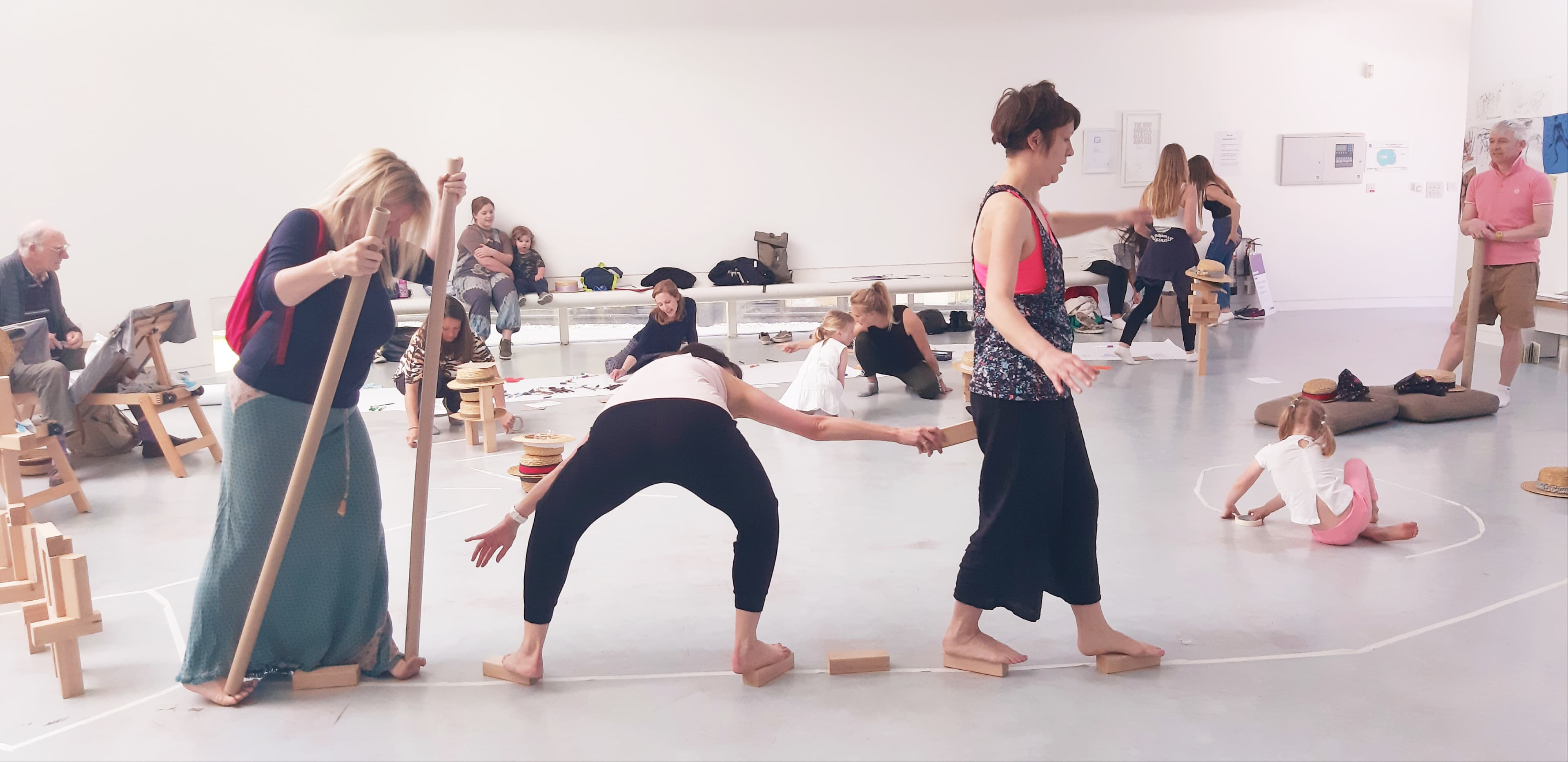 People of various ages playing in a large open white art studio space